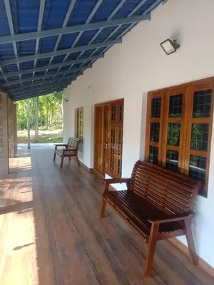 two benches in a room with wooden floors and windows at PADAVAYAL GREENS in Attappādi