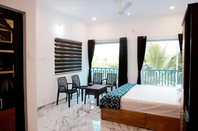 a bedroom with a bed and chairs and a window at PADAVAYAL GREENS in Attappādi