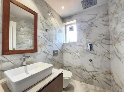 a bathroom with a sink and a toilet and a mirror at Gulzar 2BHK Service Apartment, kannur in Kannur