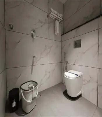 a bathroom with a toilet and a trash can at Mayo Suites in Palakkad