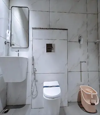 a white bathroom with a toilet and a mirror at Mayo Suites in Palakkad