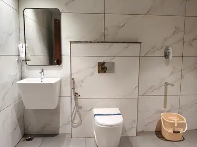 a bathroom with a toilet and a sink and a mirror at Mayo Suites in Palakkad