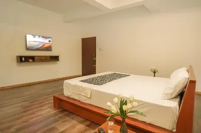 a bedroom with a bed and a tv on a wall at Richfields in Ooty
