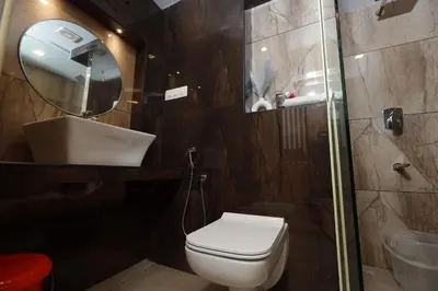 a bathroom with a toilet and a sink and a mirror at Liwa Tower Hotel & Business Center in Kunnamkulam