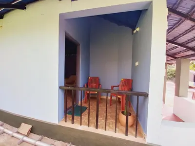 a balcony of a house with two chairs and a table at Nature Greens Cottage in Madikeri