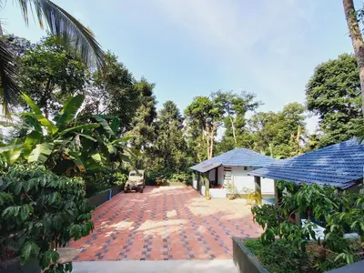 a driveway of a house with a car parked on it at Nature Greens Cottage in Madikeri