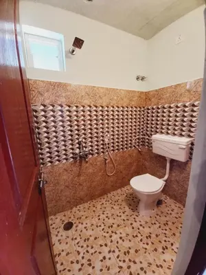 a bathroom with a toilet and a shower at Nature Greens Cottage in Madikeri