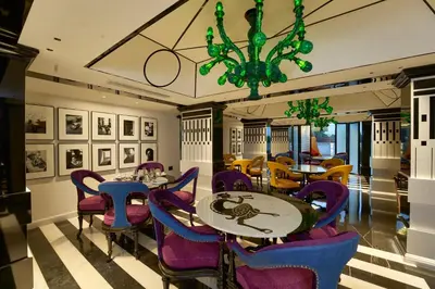 a dining room with purple chairs and tables and a chandelier at Noah Sky Suites in Cochin
