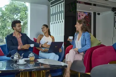 three people sitting around a table with a laptop at Noah Sky Suites in Cochin