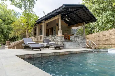 a house with a pool and chairs next to a building at Akshaya Bungalow by Sparsa in Sethumadai