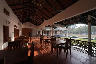 a restaurant with wooden tables and chairs and a patio at Meleppura Heritage Homestay in Chāvakkād
