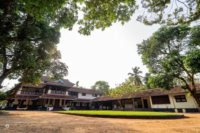 a building with trees in front of it at Meleppura Heritage Homestay in Chāvakkād