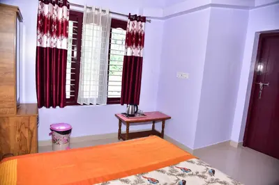 a bedroom with a bed and a table and windows at Madhuvana Homestay Coorg in Madikeri