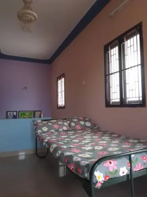 a bedroom with a bed in a room with windows at Aathira's 2 Bedroom house @ Heart of Coimbatore in Coimbatore