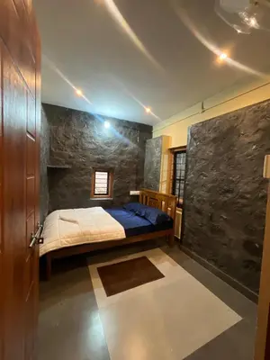 a bedroom with a bed and a stone wall at Elora Resort Wayanad in Kalpetta