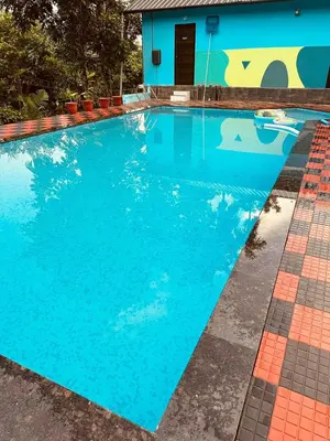 a swimming pool with blue water in front of a house at Elora Resort Wayanad in Kalpetta
