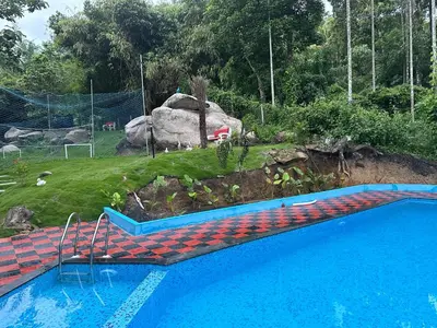 a swimming pool in a yard with a rock at Elora Resort Wayanad in Kalpetta