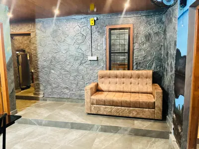a brown couch in a room with a stone wall at Elora Resort Wayanad in Kalpetta