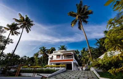 a house with palm trees in front of it at The Vogue - Luxury Private Pool Villa , Athirappilly in Athirappilly