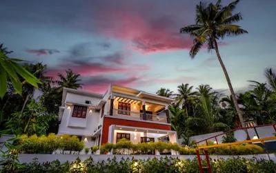 a house on the beach with a palm tree at The Vogue - Luxury Private Pool Villa , Athirappilly in Athirappilly