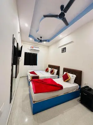 two beds in a room with a ceiling fan at ROSEPARK INN in Mysore