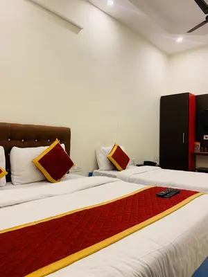 two beds in a room with red and yellow pillows at ROSEPARK INN in Mysore