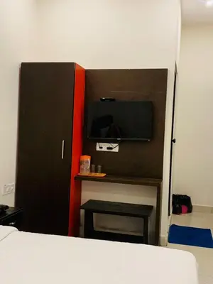 a bedroom with a bed and a tv and a table at ROSEPARK INN in Mysore
