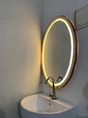 a bathroom sink with a round mirror on the wall at ZAHIR RESIDENCY in Kondotti