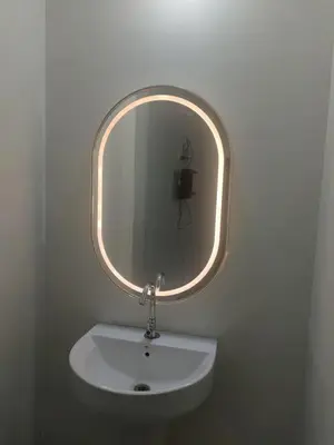 a bathroom sink with a round mirror on the wall at ZAHIR RESIDENCY in Kondotti