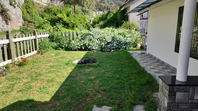 a backyard with a fence and a yard with grass and flowers at Vue D'en Haut, Ooty,India in Ooty