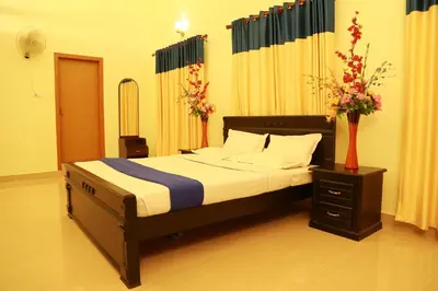 a bedroom with a bed and a vase of flowers at Dreamnest Residency in Kalpetta