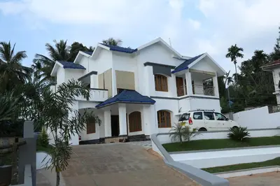 a white house with a car in front of it at Dreamnest Residency in Kalpetta