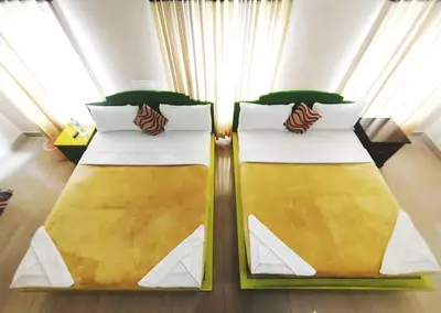 two beds in a room with yellow and white at Dreamnest Residency in Kalpetta