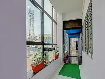 a hallway with a large window with a green rug at Hotel O Easy Stay Mysore in Mysore