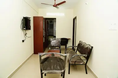 a room with chairs and a tv and a ceiling at Meadow Comfort Stay in Coimbatore