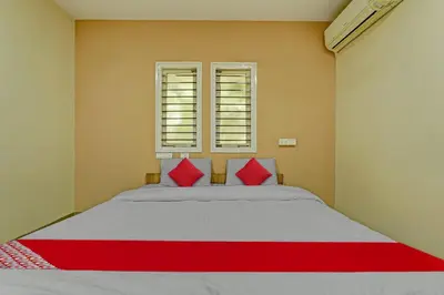 a bedroom with a large bed with red pillows at Super Hotel O Indra Suites in Mysore