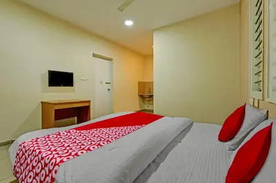a bedroom with a bed with a red and white comforter at Super Hotel O Indra Suites in Mysore