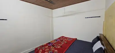 a small room with a bed with a red blanket at SPM Residency, From Live2Travel Group. in Masinagudi