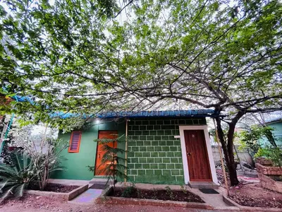 a green house with a red door under a tree at SPM Residency, From Live2Travel Group. in Masinagudi