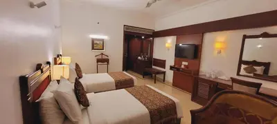 a hotel room with two beds and a television at ASHOKA INN in Trichūr