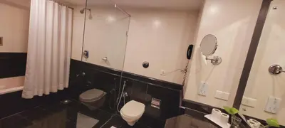 a bathroom with two toilets and a mirror at ASHOKA INN in Trichūr