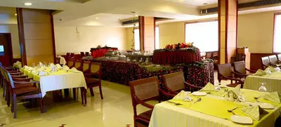 a restaurant with tables and chairs with yellow tablecloths at ASHOKA INN in Trichūr