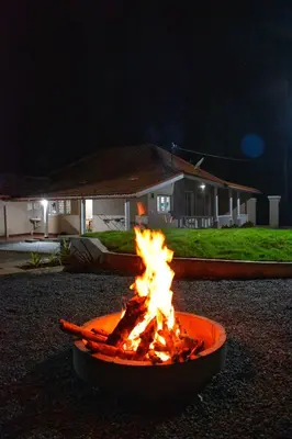 a fire pit in front of a house at night at Rochas Valley Homestay in Suntikoppa