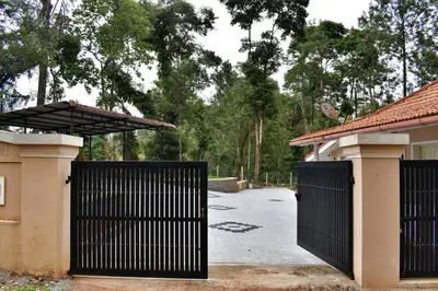 a gate to a house with a driveway at Rochas Valley Homestay in Suntikoppa