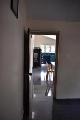 a hallway with a door open to a room with a table at Rochas Valley Homestay in Suntikoppa