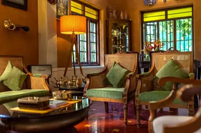 a living room with chairs and a table and windows at Sukrutham Farmstay in Trichūr
