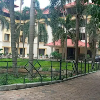 a fence in front of a building with palm trees at Kottaram Hotels Ottaplam in Palakkad
