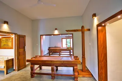 a room with a wooden table and a piano at Softouch Ayurveda Village Kerala in Kizhake Chālakudi
