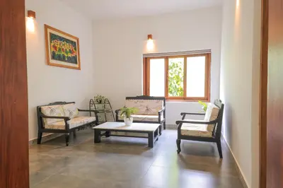 a living room with three chairs and a coffee table at Softouch Ayurveda Village Kerala in Kizhake Chālakudi