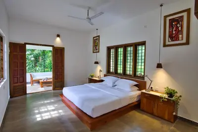 a bedroom with a large white bed and a patio at Softouch Ayurveda Village Kerala in Kizhake Chālakudi